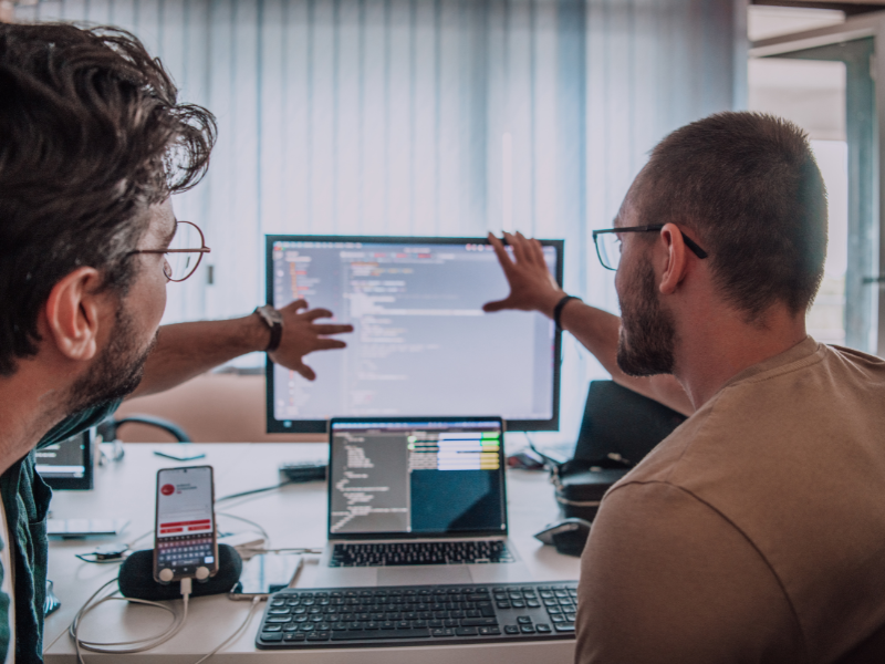 Two individuals discussing and looking at a monitor together. 
